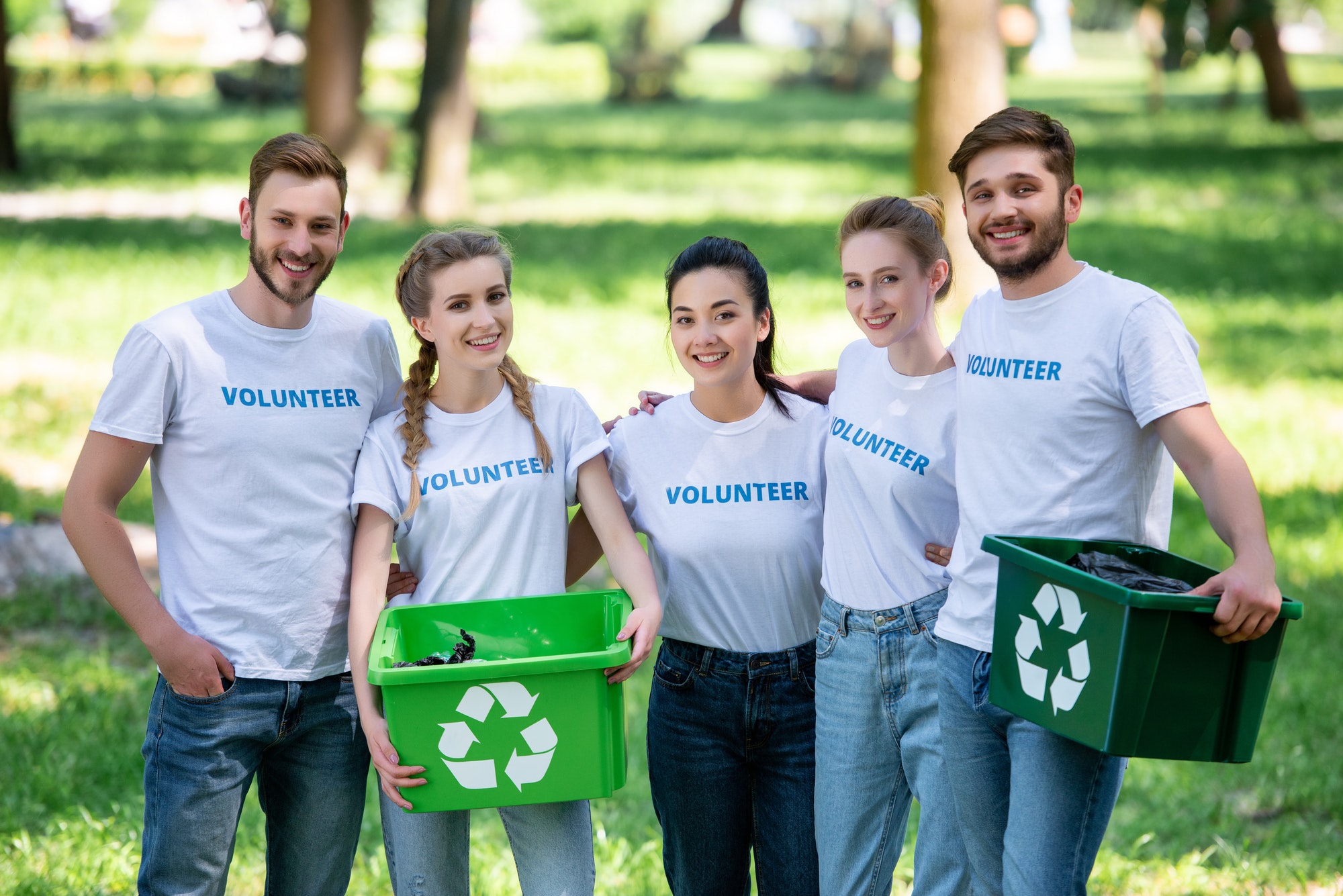 young-volunteers-with-green-recycling-boxes-for-trash-standing-in-park.jpg